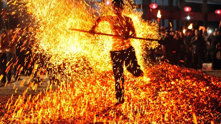 A man walks through burning charcoal as he participates in the traditional ritual called "Lianhuo", or "fire walking", in Pan'an county, Zhejiang province November 25, 2013. Lianhuo, a traditional local ritual which was listed in 2005 as an intangible cultural heritage of the province, usually requires dozens of men to walk past burning charcoal or firewood barefooted, as a way to ward off evil and pray for good fortune. Picture taken November 25, 2013.