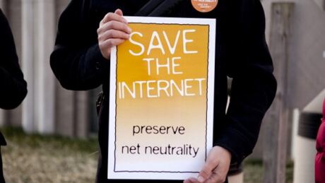 Timothy Karr of the Free Press holds a sign in support of net-neutrality before a hearing at the U.S. Federal Communications Commission in Washington, D.C., U.S., on Tuesday, Dec. 21, 2010. U.S. regulators banned Internet service providers led by AT&T Inc. and Comcast Corp. from blocking or slowing Web content sent to homes and businesses, while allowing mobile phone companies to put limits on traffic. Photographer: Andrew Harrer/Bloomberg via Getty Images FCC NET NEUTRALITY