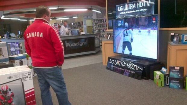 Brad Farmer, manager of Krazy Kiley's in Saskatoon, takes in the semi-final men's hockey game on a big screen.