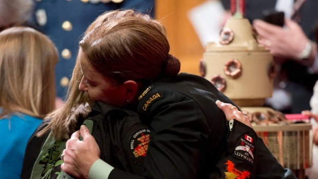 Warrant Officer Renay Groves hugs a mother prior to a ceremony in the Senate during a National Day of Honour.