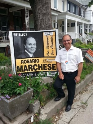 Rosario Marchese stands next to his sign