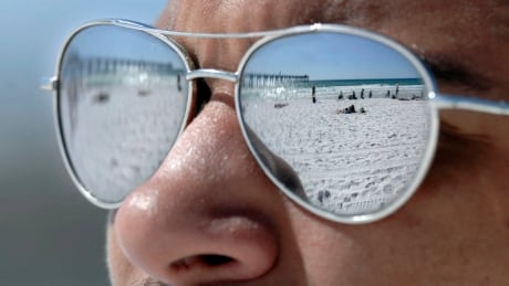 Blue sky, white sand and spring breakers are reflected in the sunglasses of University of Florida student Luc Lawrence as he and friends enjoy a warm sunny day on Okaloosa Island beach in Fort Walton Beach, Fla. on Monday, March 5, 2012. Fla. Daily Life