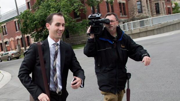 Former Conservative party staffer Michael Sona runs past a news videographer while leaving court in Guelph, Ont. on Thursday.