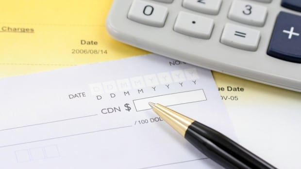 A blank cheque sits on a table, with a pen hovering above it.