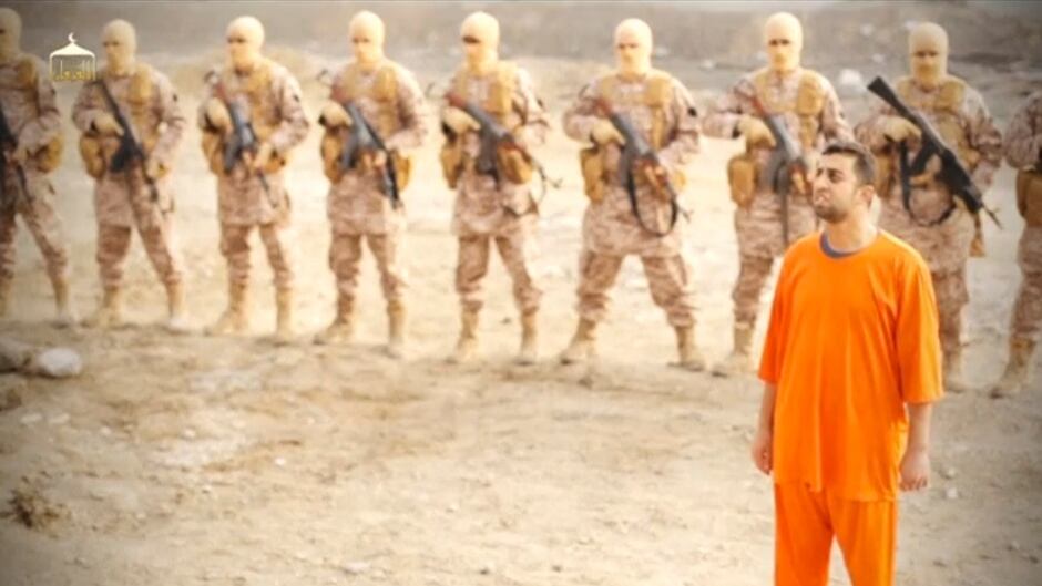 A man purported to be Islamic State captive Jordanian pilot Muath al-Kasaesbeh stands in front of armed men in this still image from an undated video filmed from an undisclosed location made available on social media on February 3, 2015. According to Aymenn Jawad Al-Tamimi, the soundtrack to this video is a jihadi nasheed, or song, called "Soon, Soon".