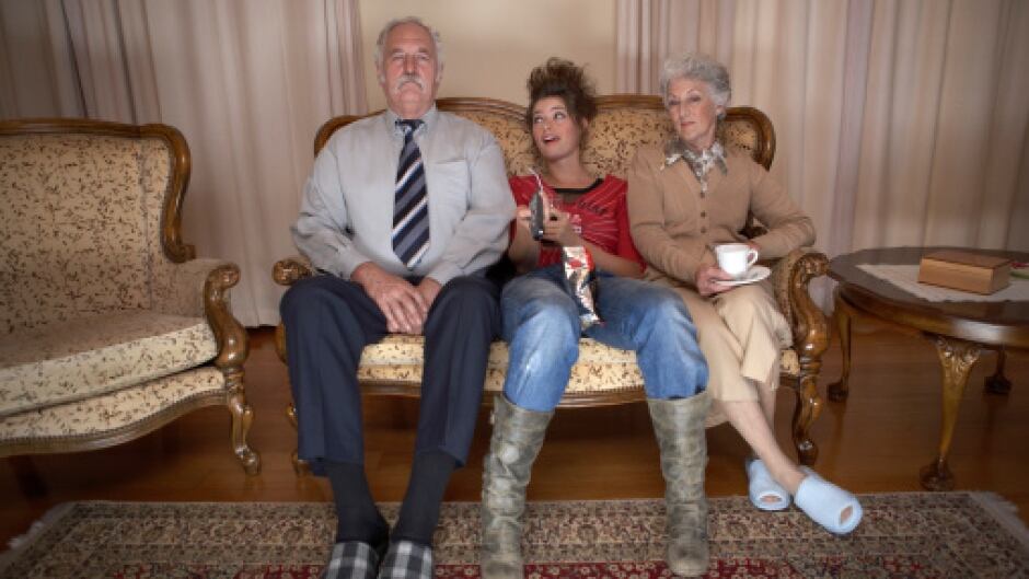 Adult daughter sitting between senior couple on settee