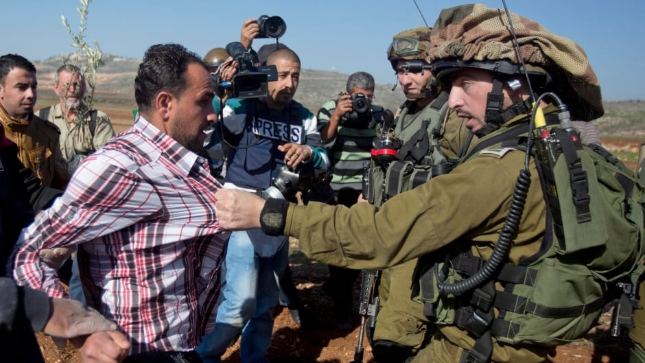 A confrontation between an Israeli soldier and a Palestinian during a demonstration against Israeli settlements in the village of Turmus Aya near the West Bank city of Ramallah, Wednesday, Dec. 10, 2014.