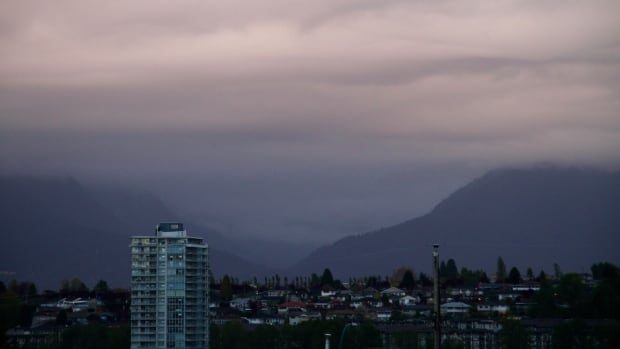 Clouds and a little rain hang around the North Shore mountains, Wednesday morning. A cityscape photograph of the City of Vancouver, framed by the North Shore Mountains under heavy skies.