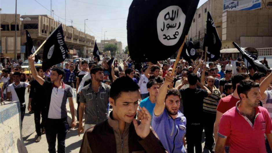 In this June 16, 2014 file photo, demonstrators chant pro-Islamic State group, slogans as they carry the group's flags in front of the provincial government headquarters in Mosul.