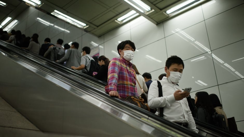 Commuters wearing face masks ride an escalator in a subway in central Seoul, South Korea on June 5, 2015.