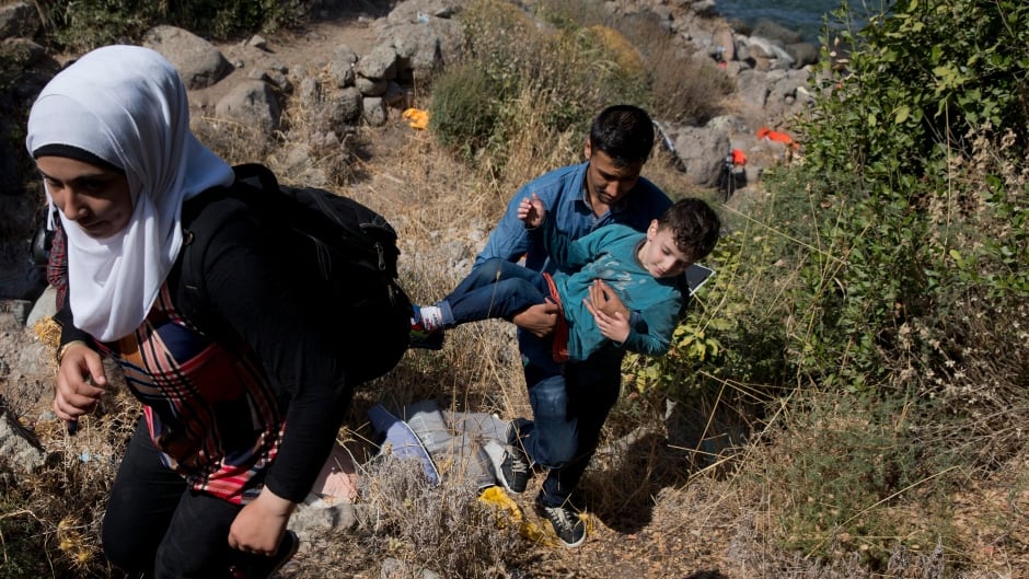 Syrian refugees walk up a hill as they arrive on a dinghy after crossing from Turkey to Lesbos island, Greece, Friday, Sept. 11, 2015.