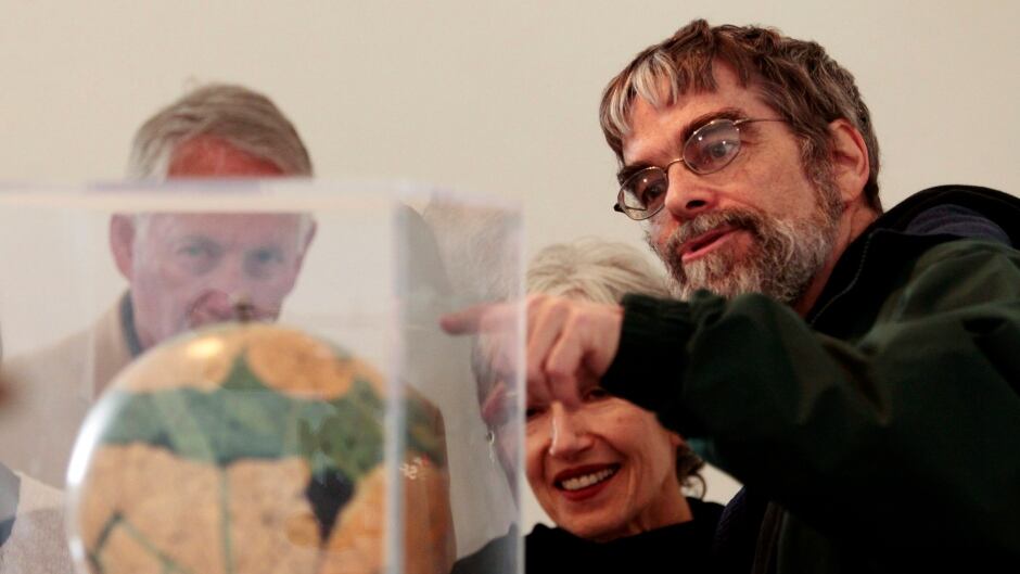 In this April 15, 2011 file photo, Brother Guy Consolmagno, a Jesuit astronomer at the Vatican's Observatory, right, shows to visitors the Globe of planet Mars. (AP Photo/Gregorio Borgia)