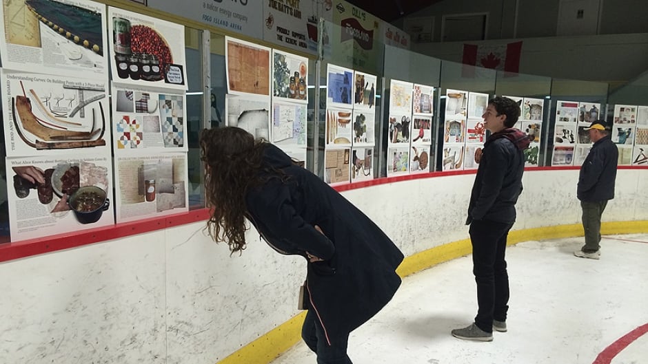 Visitors view pages from "The Encyclopedia of Local Knowledge in Fogo", on display at the Fogo Island hockey rink.