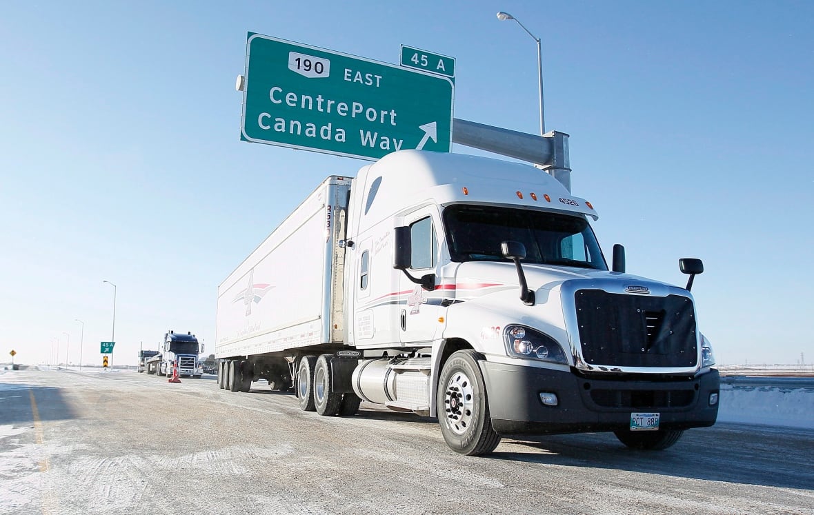 A semi-truck is driving under a sign that reads "CentrePort Canada Way."