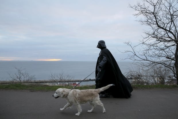 Darth Mykolaiovych Vader walks his golden retriever in Odessa in December