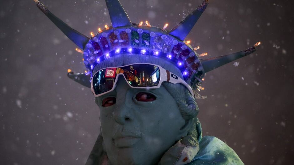 A man is seen posing as the Statue of Liberty during a snow storm in Times Square.