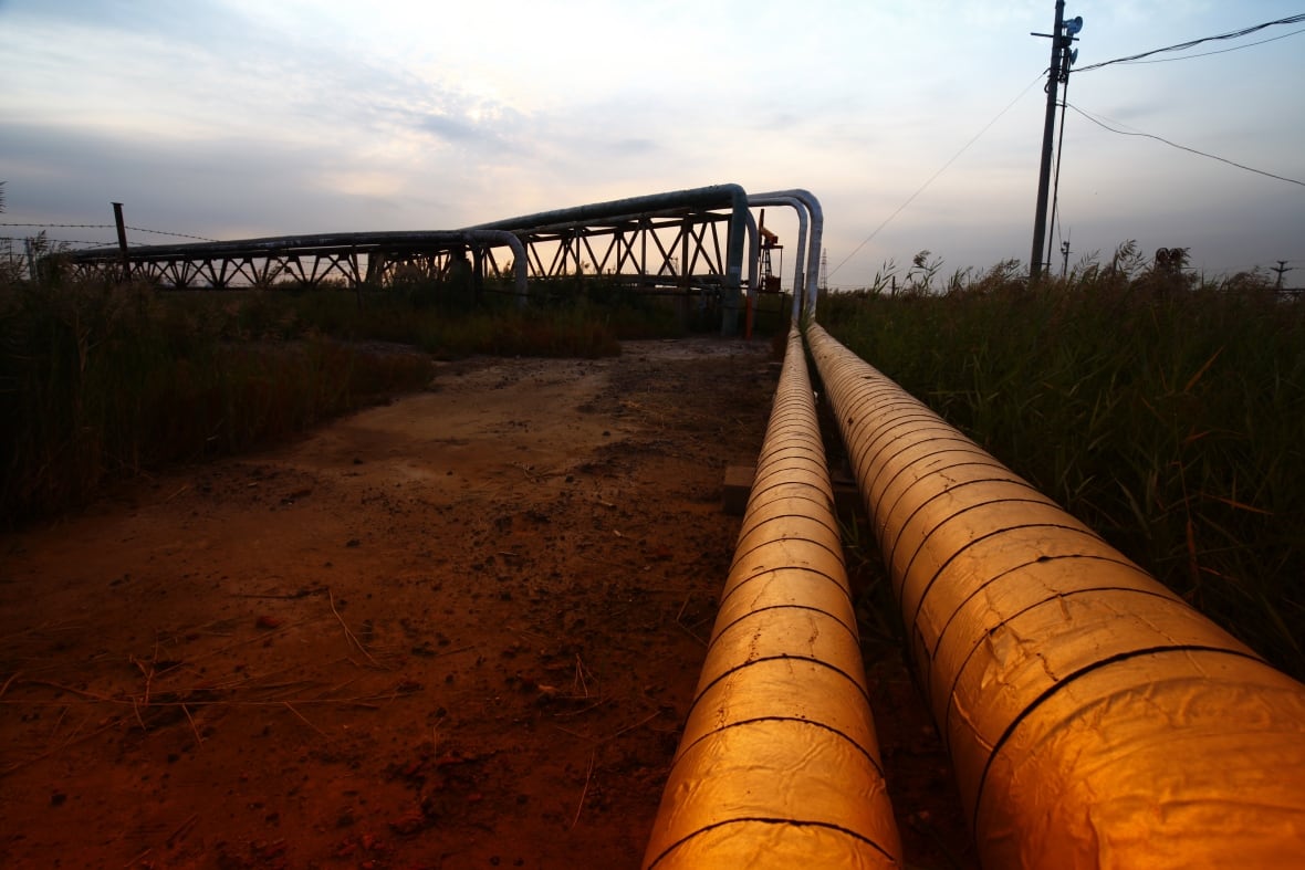 A long pipeline sits above a dirt field. It's dusk outside and the sky is a grey blue.