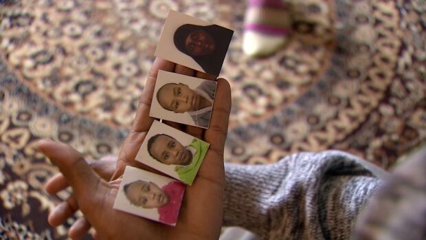 Ahmed Abdi holds photos of his wife and children