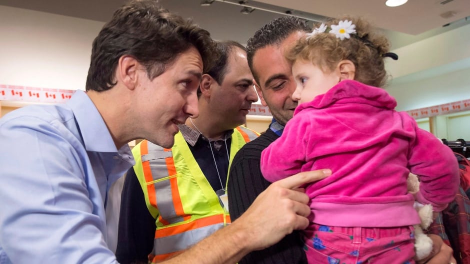 Canadian Prime Minister Justin Trudeau greets 16-month-old Madeleine Jamkossian, right, and her father Kevork Jamkossian, refugees fleeing the Syrian civil war, during their arrival at Pearson International airport, in Toronto, on Friday, Dec. 11, 2015.