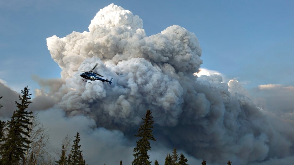 A helicopter flies past a wildfire in Fort McMurray, Alta., on Wednesday May 4, 2016.