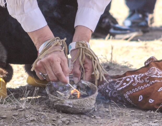 Phillips sets fire to the sage in her smudging bowl