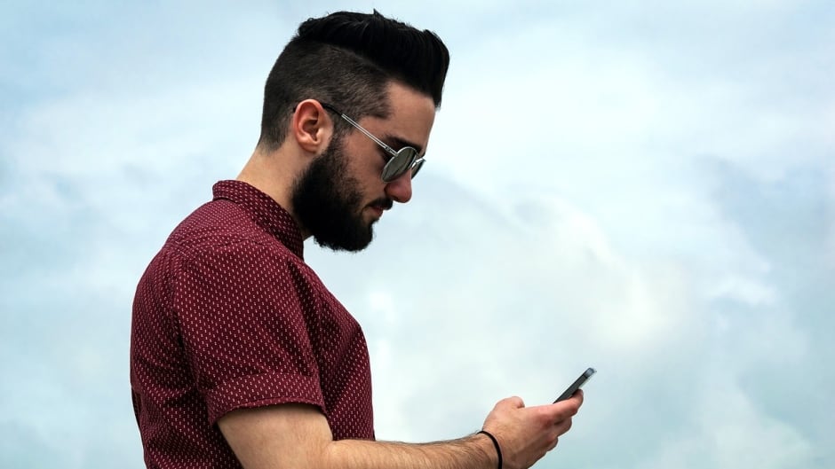 A millennial looks intently at his smartphone.