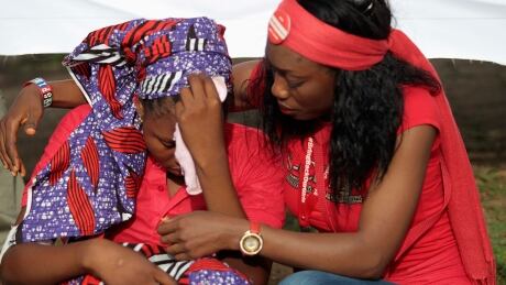 Isaac Rebecca, one of the girls that escaped from the Boko Haram camp is comforted during a protest march, in continuation of the Global Week of Action to commemorate six months since the abduction of the 219 Chibok school girls, organized by the Abuja "Bring Back Our Girls" protest group to the Presidential Villa, in Abuja October 14, 2014. NIGERIA-PROTEST/