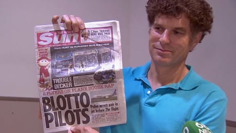 Passenger David McInnis holds up Tuesday's edition of the Scottish Sun, which put the story about impaired charges against two Canadian Air Transat pilots on its front page. McInnis said passengers weren't told Monday why their flight was delayed. Air Transat Passengers charged