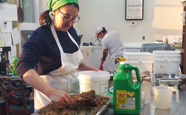 Volunteer scoops black bean sweet potato mix Hillside Festival food prep