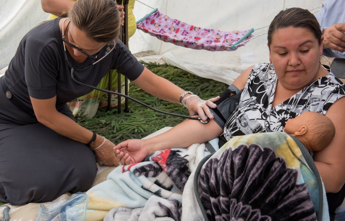 A nurse caretaking a Cree mother and her baby. 