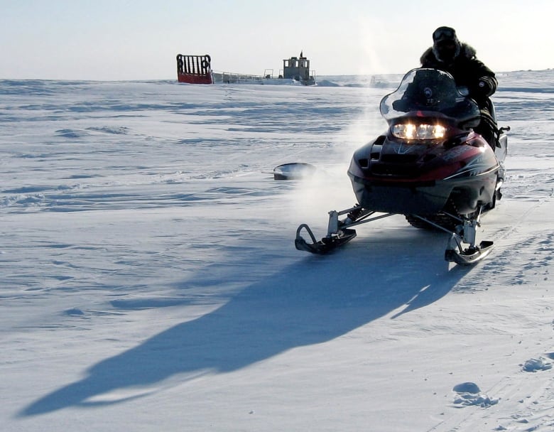 A man rides a snowmobile over icy terrain.