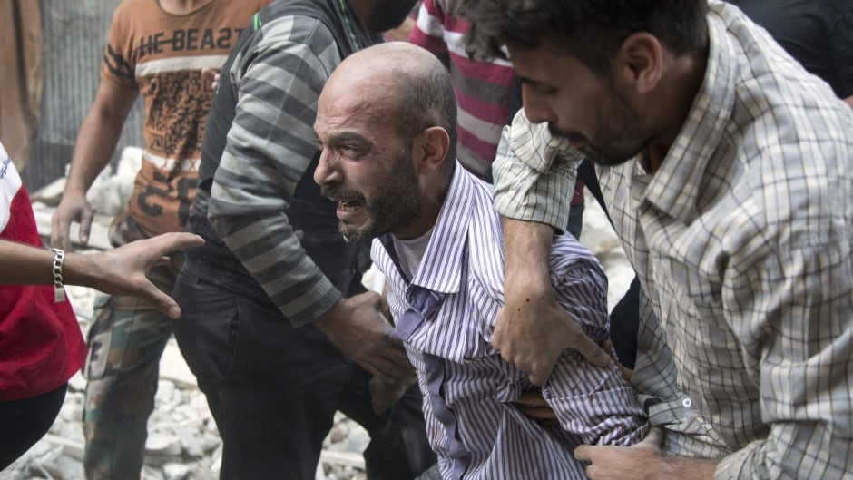 A grief-stricken Syrian man is comforted by people as rescuers pull the body of his daughter from the rubble of a building in the rebel-held neighbourhood of Al-Shaar, Aleppo, Sept. 27, 2016.
