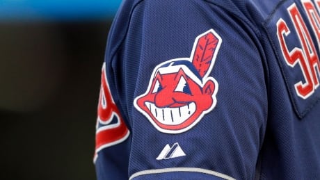 The Cleveland logo is seen on the uniform sleeve of third base coach Mike Sarbaugh during a game against the San Diego Padres in Cleveland during the 2014 season. Cleveland mascot