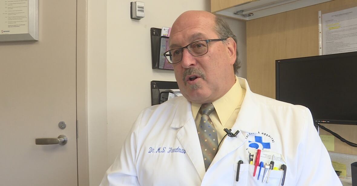 A man speaking in a doctors coat. 