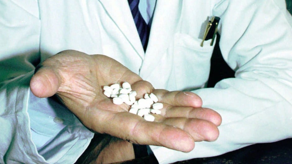 In this 1995 file photo, inventor of the RU-486 abortion-inducing drug, Professor Emile-Etienne Beaulieu, holds the pills in Paris. More than 25 years later, the abortion pill is now available in Canada.