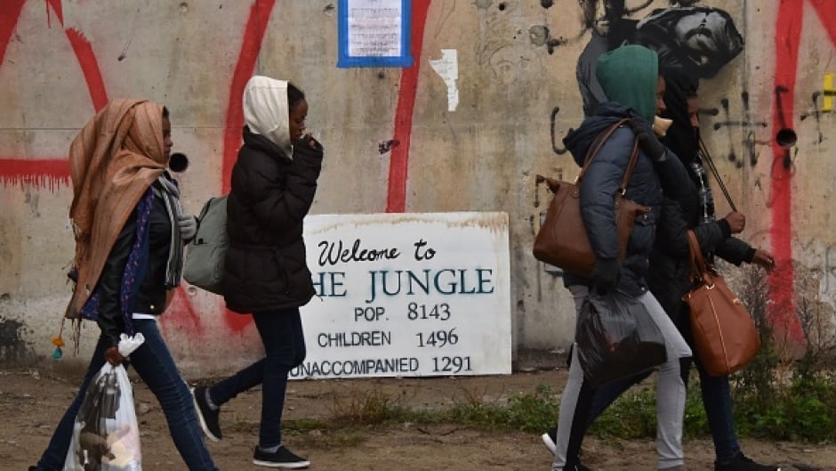 Migrants walk towards an official meeting point set by French authorities as part of the full evacuation of the camp in Calais on October 24, 2016.