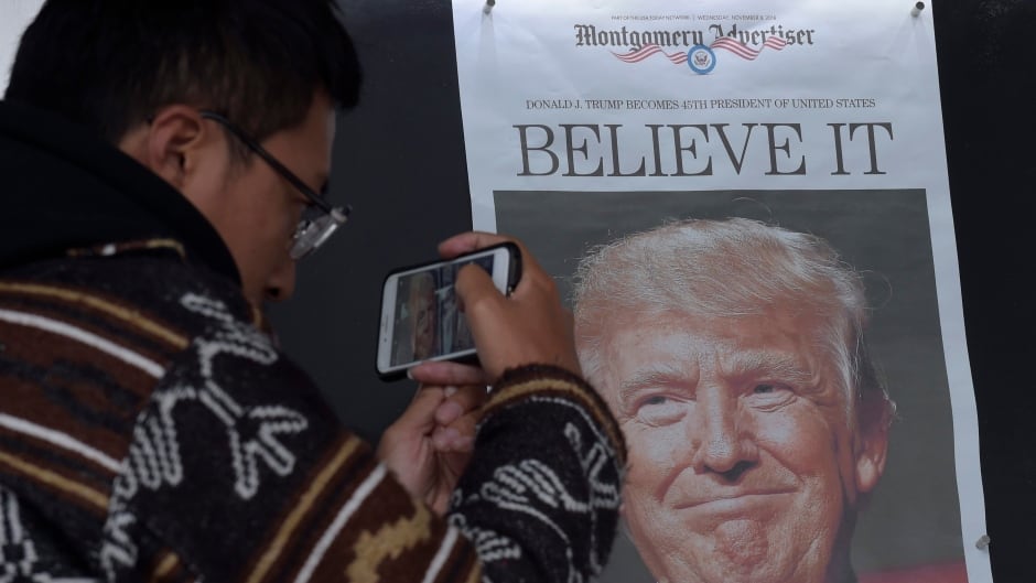 Zheng Gao of Shanghi, China, photographs the front pages of newspapers on display outside the Newseum in Washington, Wednesday, Nov., 9, 2016, the day after Donald Trump won the presidency. (AP Photo/Susan Walsh)