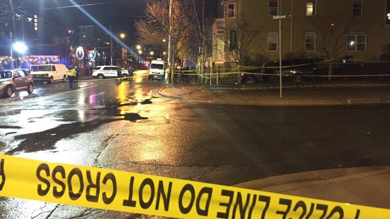 Police tape is shown, along with several police vehicles, at an evening crime scene.