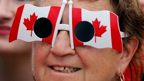 A woman wears sunglasses in the shape of Canadian flags during Canada Day celebrations on Parliament Hill in Ottawa July 1, 2014. Canadians are celebrating their country's 147th birthday. CANADA-POLITICS/