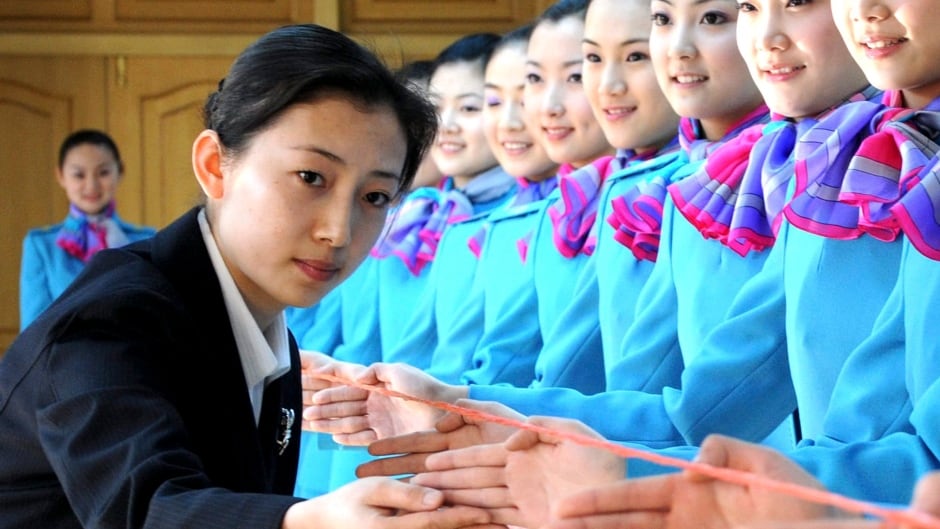 In this photo released by Xinhua News Agency, an etiquette instructor examines the gestures of students during a class in the Civil Aviation University of China, in Tianjing Municipality, north China, Tuesday, March 18, 2008. The university signed agreements with some airline companies to train some 500 apprentice flight attendants in a three-year course, Xinhua said. (AP Photo/Xinhua, Liu Haifeng)