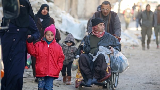 People walk as they gather to be removed from a rebel-held sector of eastern Aleppo, Syria, on Thursday