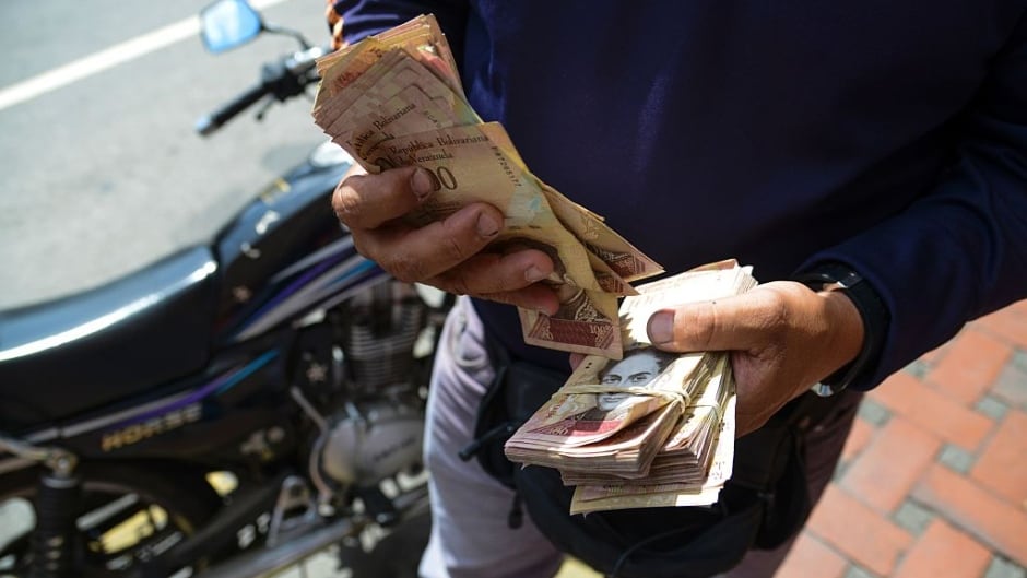 A man counts 100 Bolivar bills on the street in Caracas. Venezuelan President Nicolas Maduro signed an emergency decree ordering the country's largest banknote be taken out of circulation to thwart "mafias" of hoarding cash.