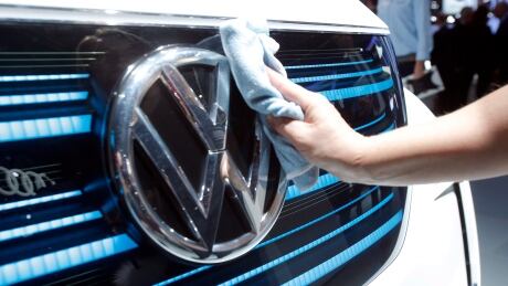 A worker shines the grill of a new Volkswagen electric car during a press conference at the Paris Motor Show in Paris, France, Thursday, Sept. 29, 2016. Many major automakers are finding the Paris auto show, held in a city whose mayor wants to ban diesels to reduce pollution, as a fine place to show off new zero-emission electric cars. France Paris Motor Show