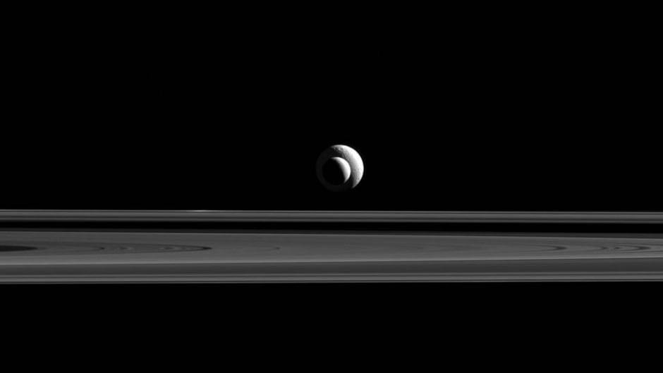 Two of Saturn's moons, Enceladus (504 kilometers across) and Tethys (1,062 kilometers across). The clean ice of Enceladus may make it a good place to search for alien life.