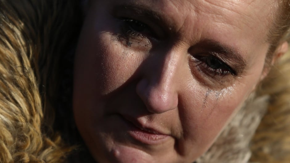 A woman reacts as she views tributes to singer George Michael outside of his home in north London, England.