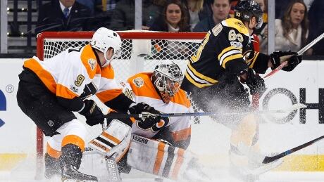Without actually shooting the puck, Boston Bruins' Brad Marchand (63) scores on Philadelphia Flyers' Michal Neuvirth (30),on Saturday in Boston. Flyers Bruins Hockey