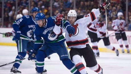 Vancouver Canucks Sven Baertschi, left, fights for control of the puck against Taylor Hall of the New Jersey Devils, during NHL action on Sunday, in Vancouver, B.C. Devils-Canucks-15012017