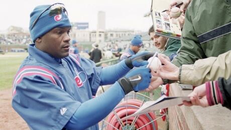 Tim Raines autographs a baseball for a fan on opening day 2001 in Chicago. raines-1180