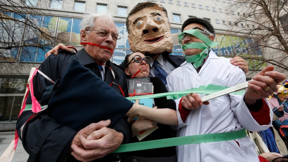 A man dressed as Canada's Prime Minister Stephen Harper (2nd R) poses after placing gags on fellow protesters dressed as a backbench Member of Parliament (L), a librarian (2nd L) and a scientist during a demonstration against the muzzling of MPs and federal government employees in Ottawa April 18, 2013.