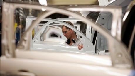 A GM plant worker in Ingersoll, Ont. installs panels and window glass on the Trim line. AUTO ASSEMBLY